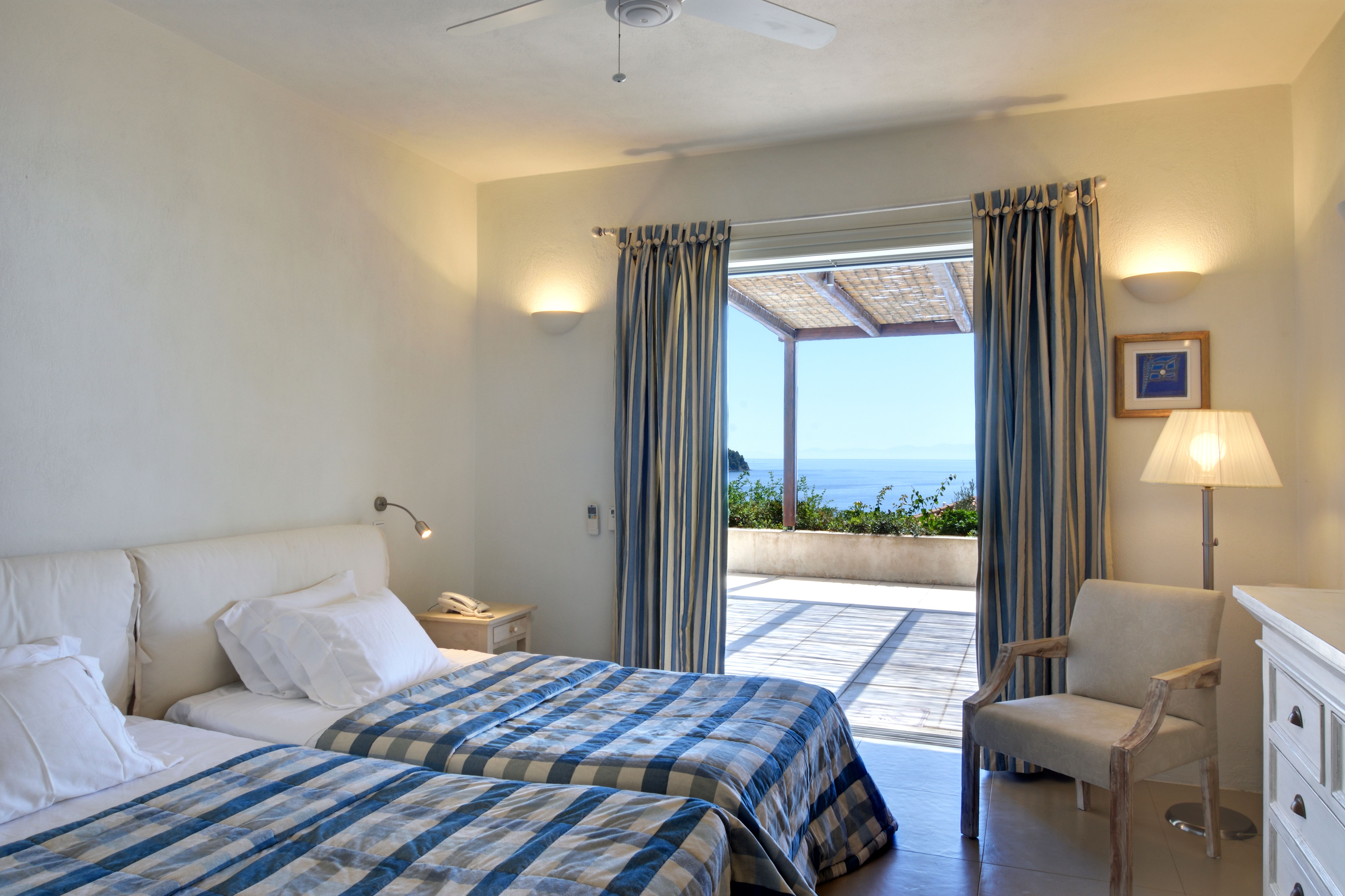A first-floor twin suite opening to the covered terrace and the sea