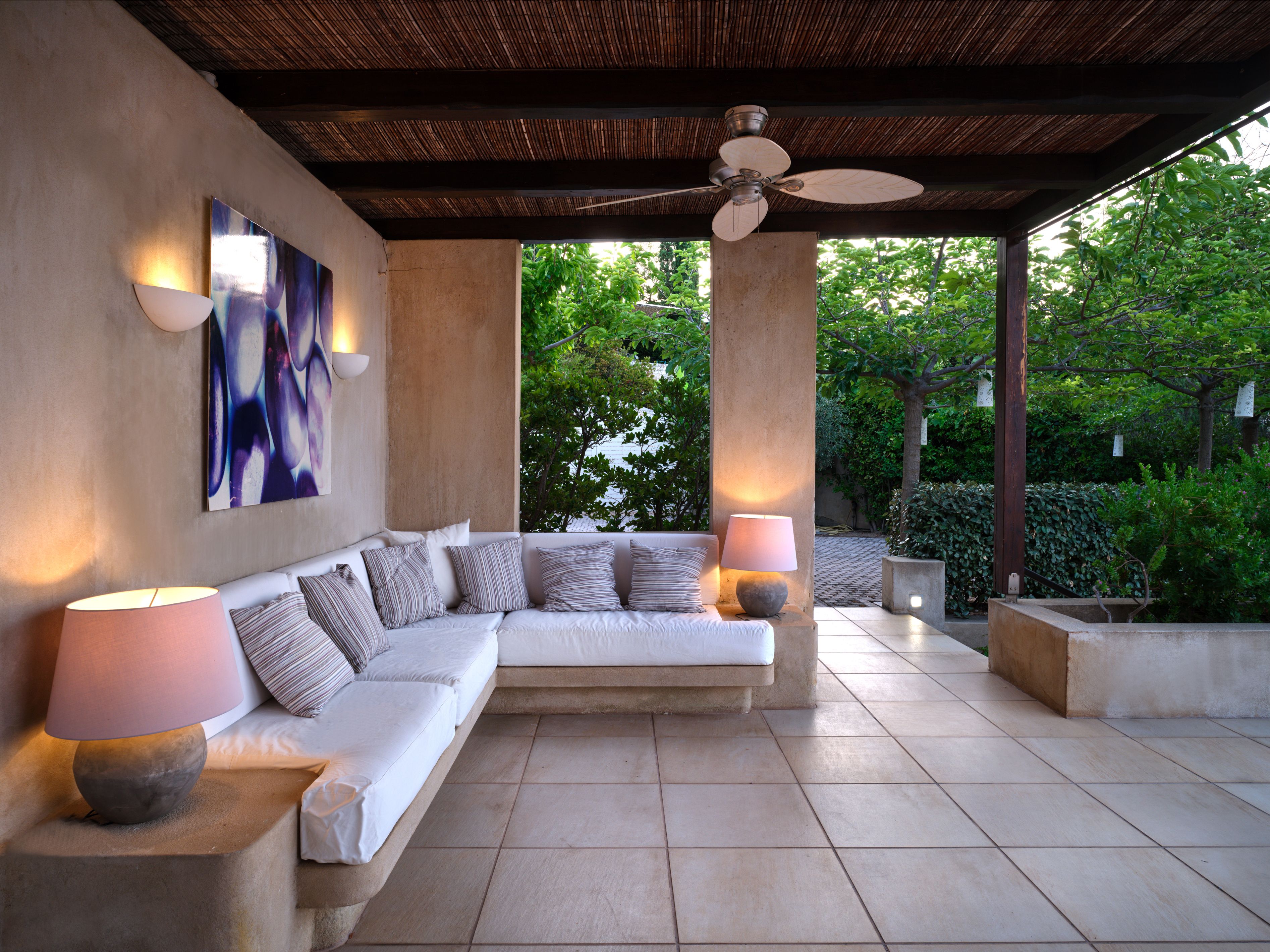 A covered lounge with lamps, open to the garden