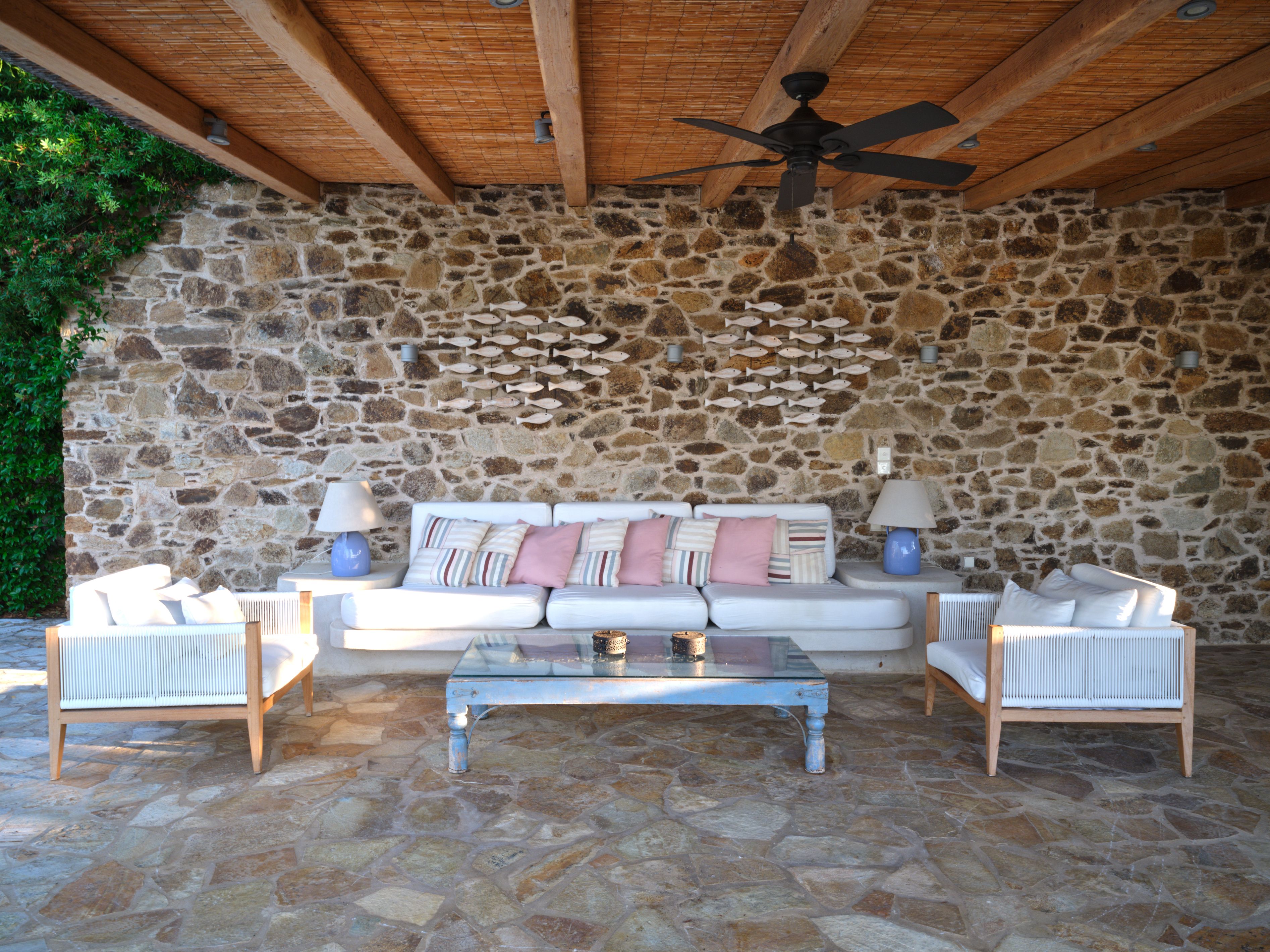 Sofas against the stone wall of the covered pool deck