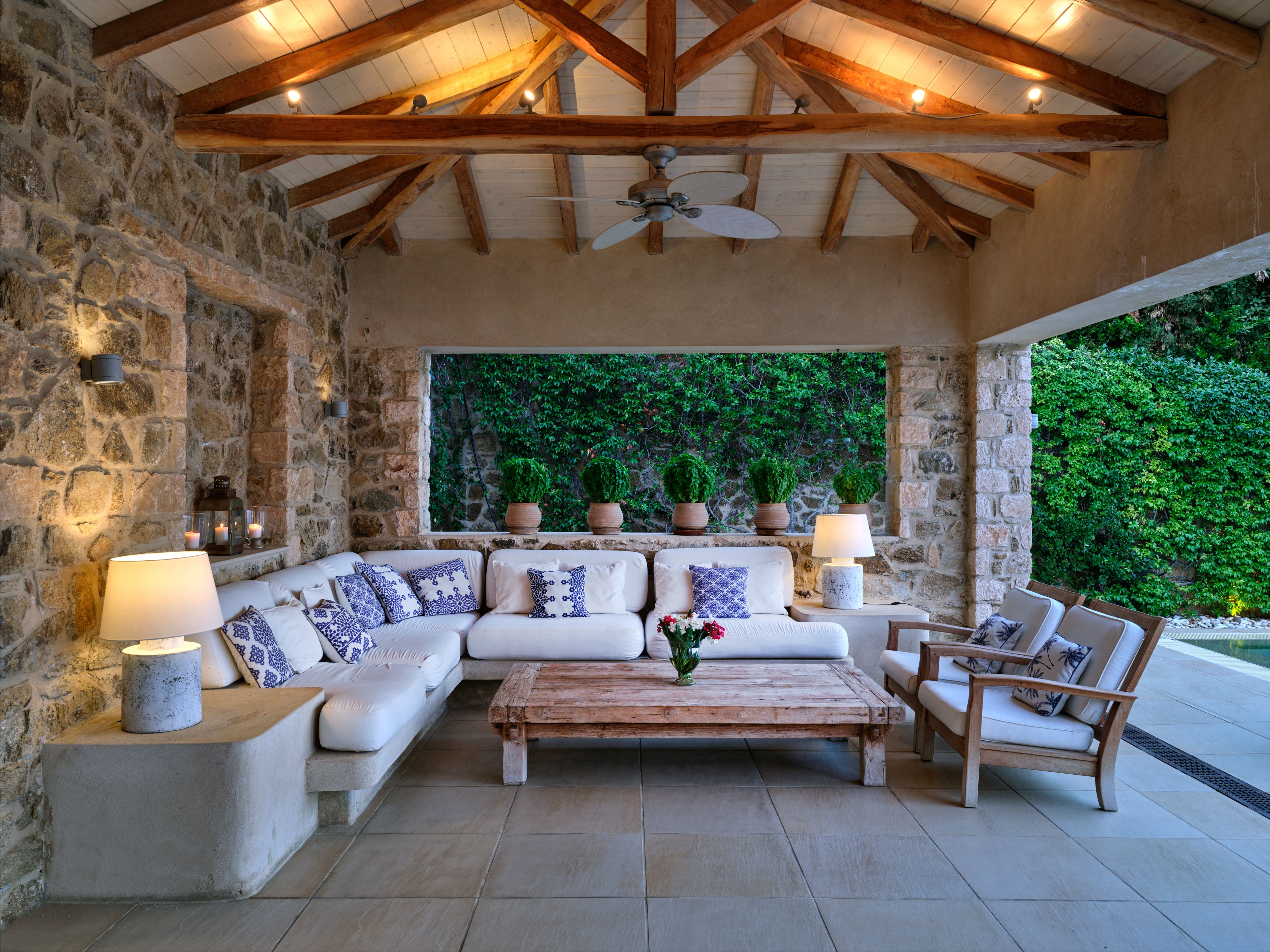 The covered outdoor living area with stone walls and sofas