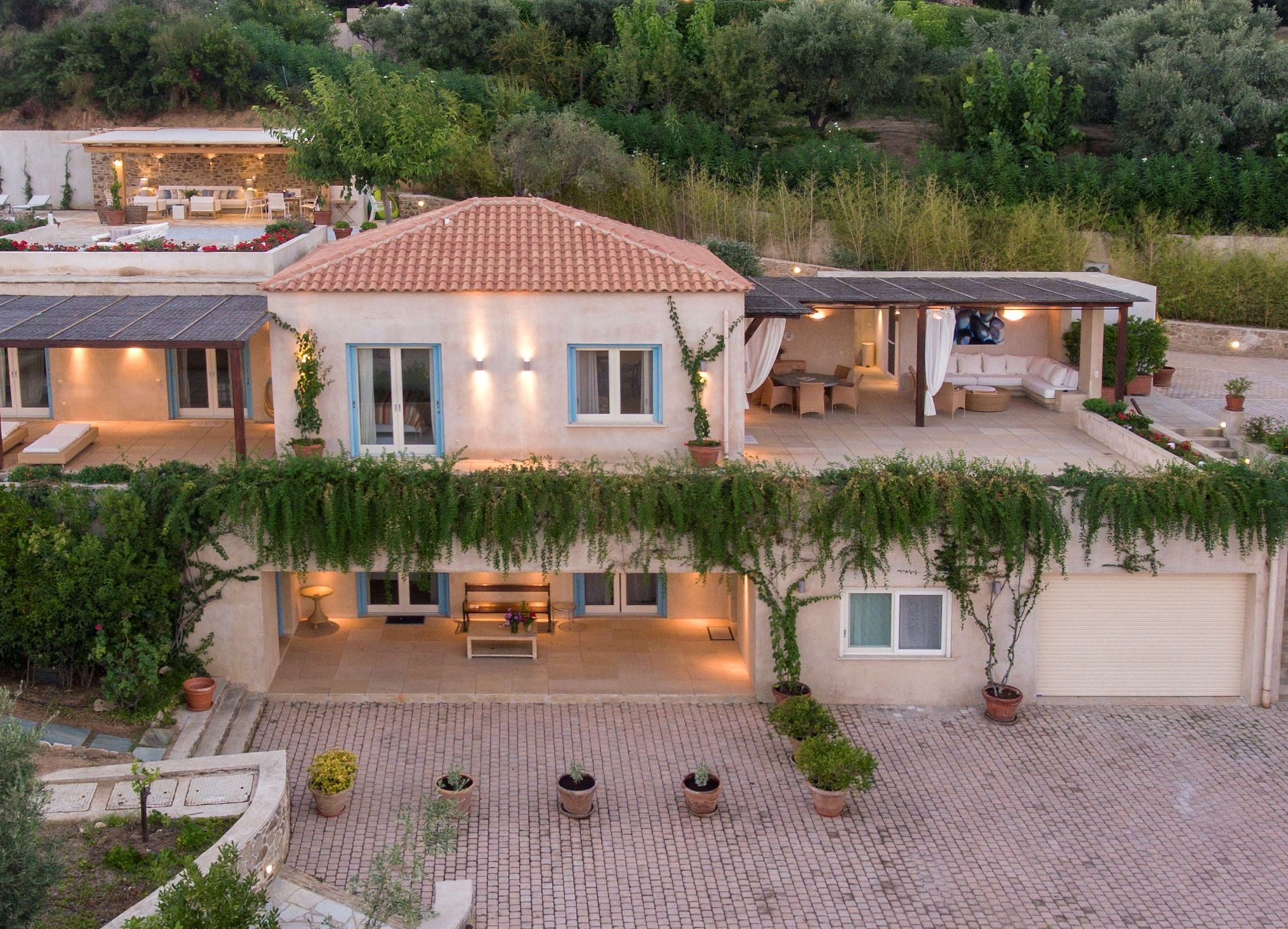 Villa GoldieLocks at dusk, its terraces lit, seen from a drone