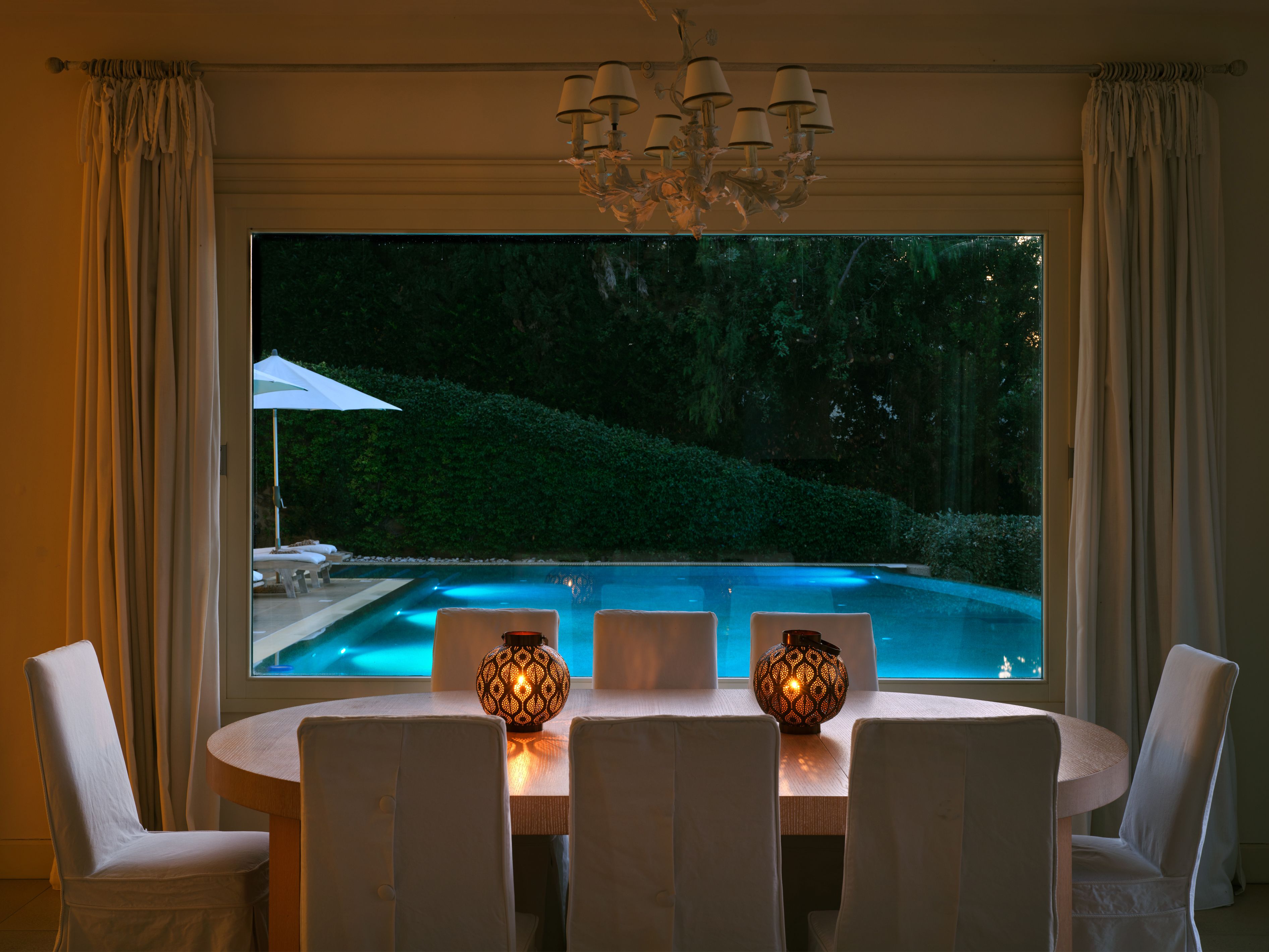 The dining room looking out to the lit pool in the evening