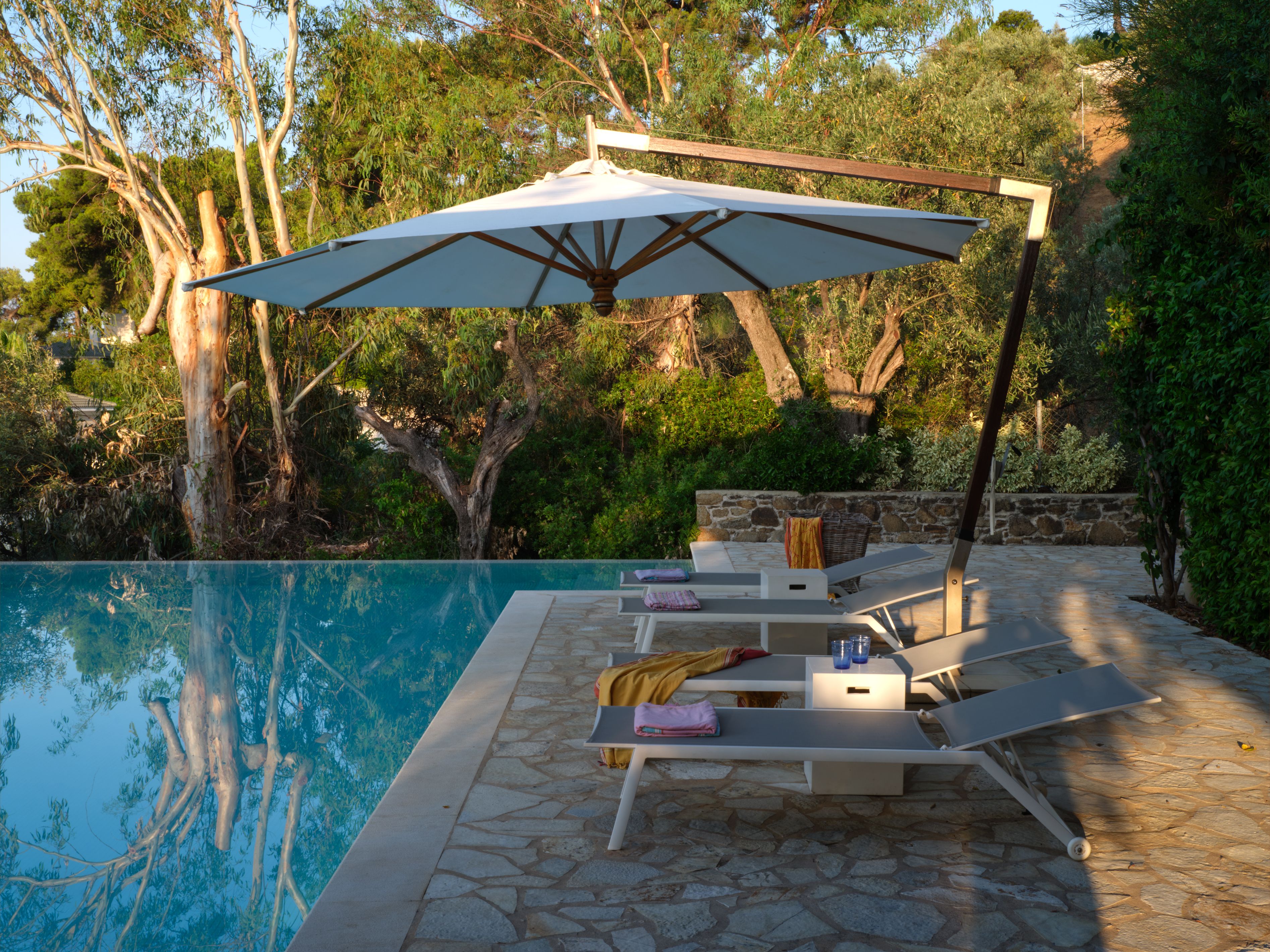 An umbrella over sunbeds at the pool edge