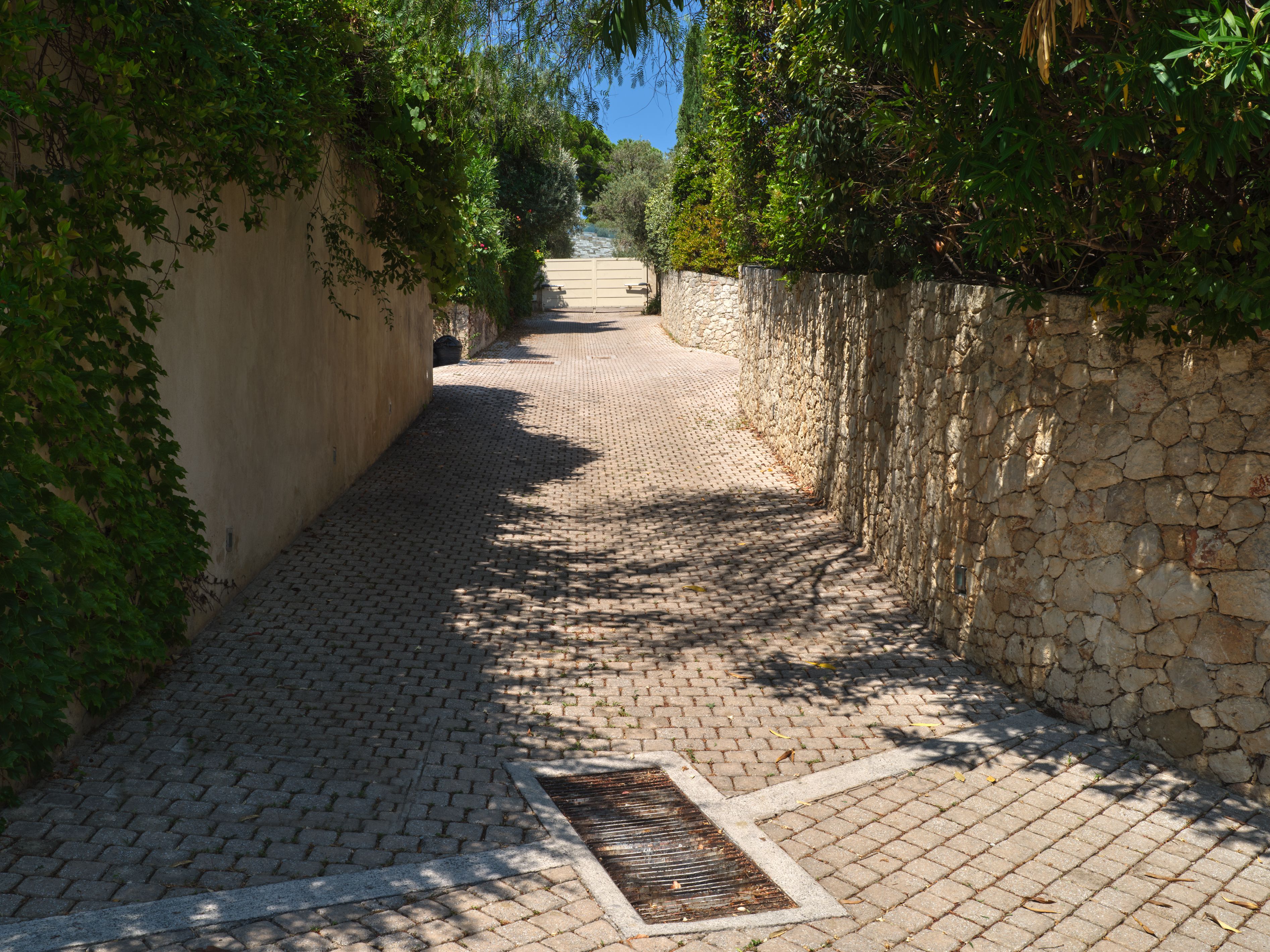 The estate’s paved pathway between stone walls, leading down towards the beach