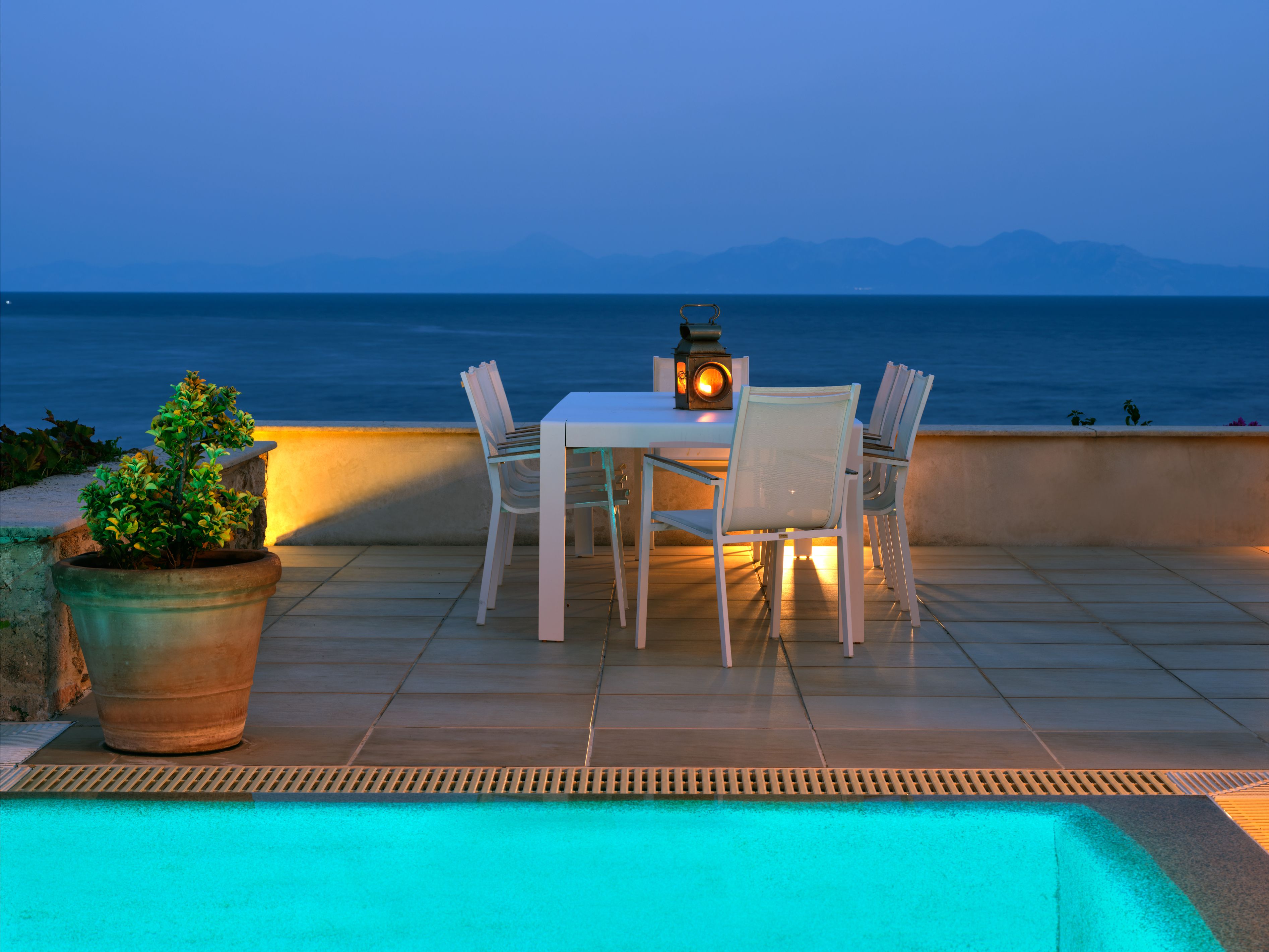 Dinner by lantern light on the pool terrace at dusk